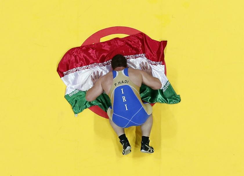 L’atleta iraniano Parviz Hadi Basmanj prega sulla bandiera dopo la vittoria nella lotta libera ai Giochi asiatici (Reuters)